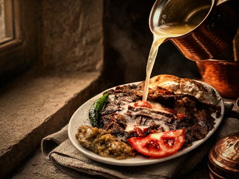 İskender: heiße Butter wird aus einem Kupfertöpfchen über Fleisch, Brot und Joghurt gegossen